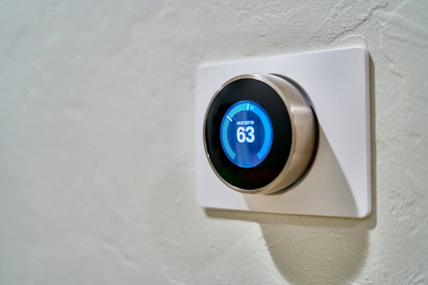 Smart thermostat mounted on a wall, helping manage home lighting and climate control during summer
