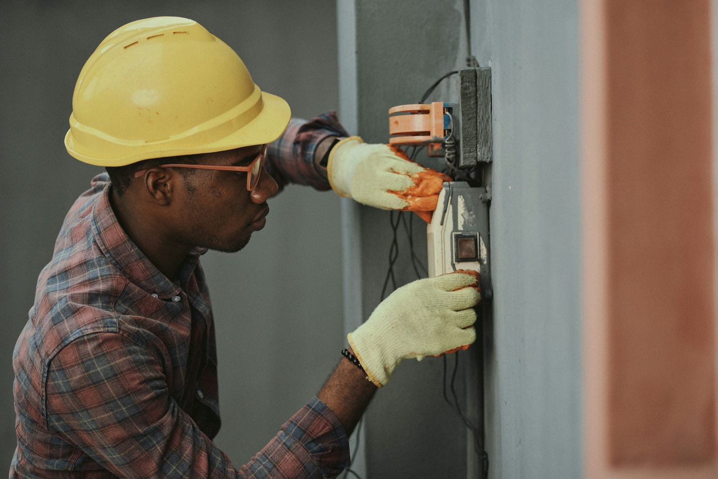 Electrician performing electrical repairs on a residential wall outlet during summer maintenance