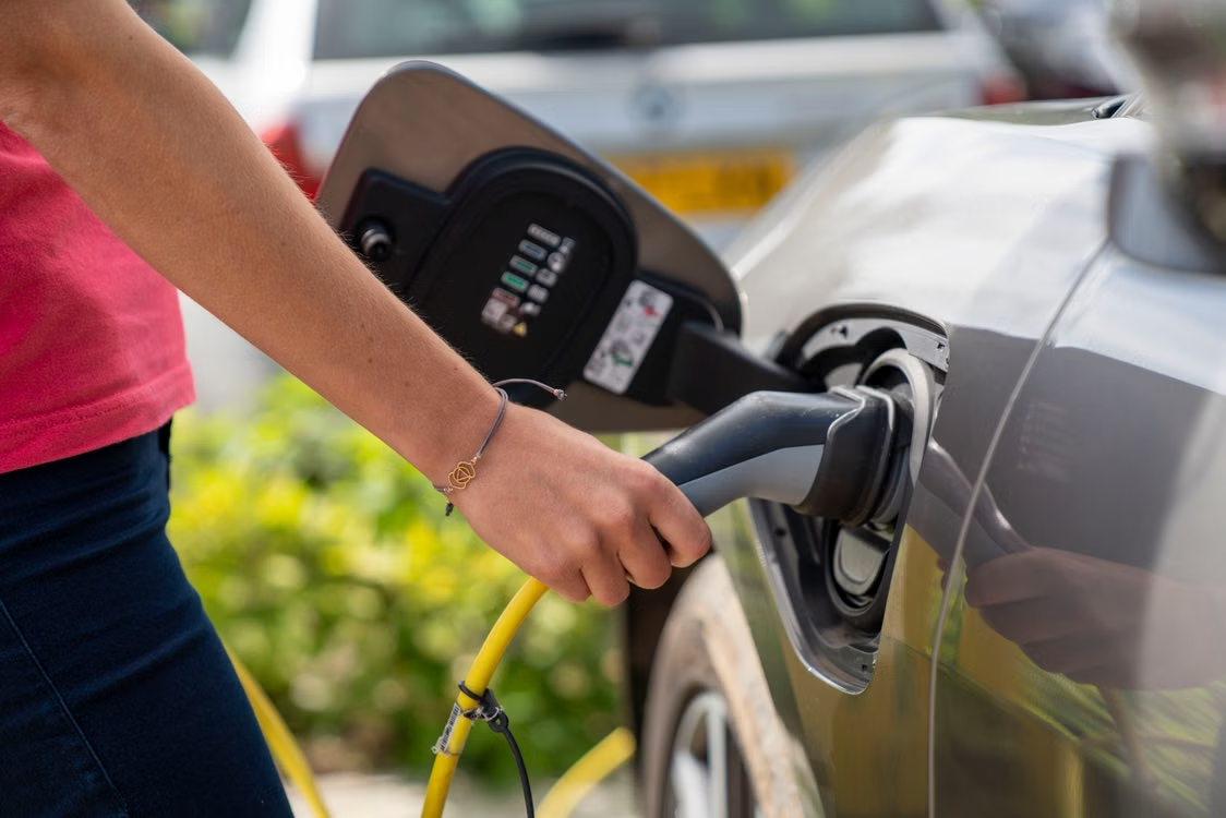 A woman uses an EV charger.