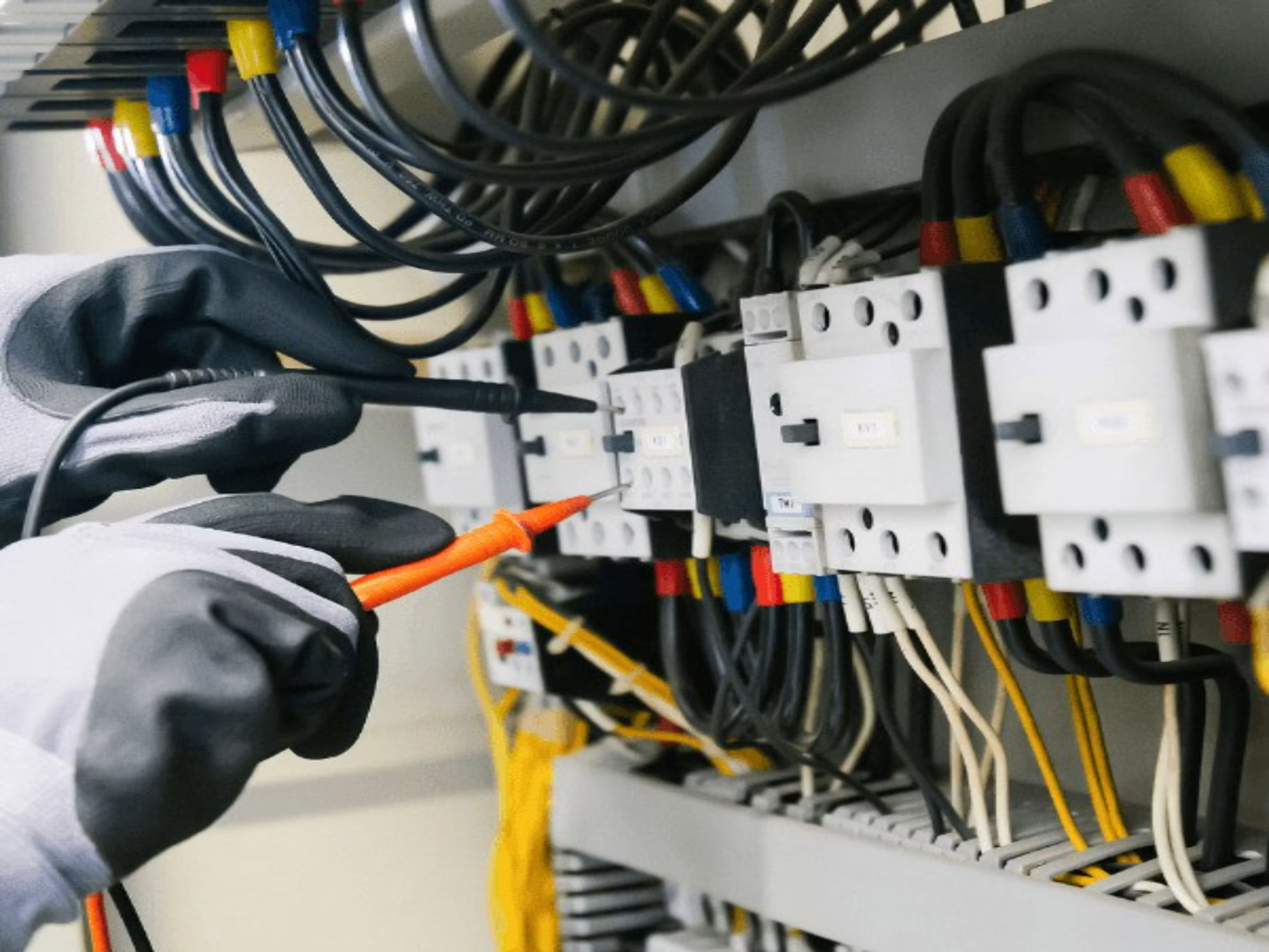 Electrician testing electrical panel connections to identify potential electrical hazards in a commercial building.